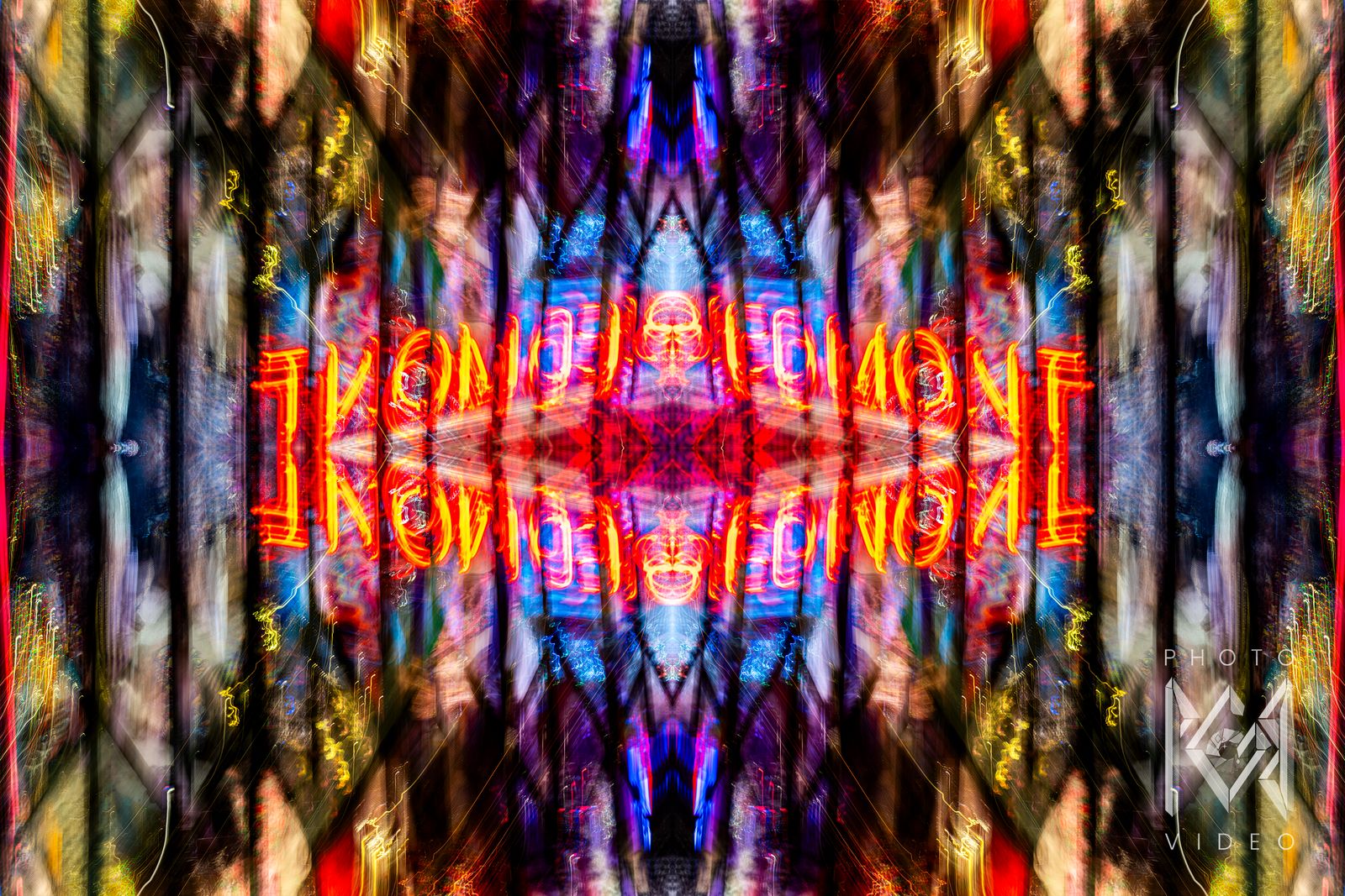 A red and yellow neon sign mirrored four ways among blurred, many-coloured storefront light