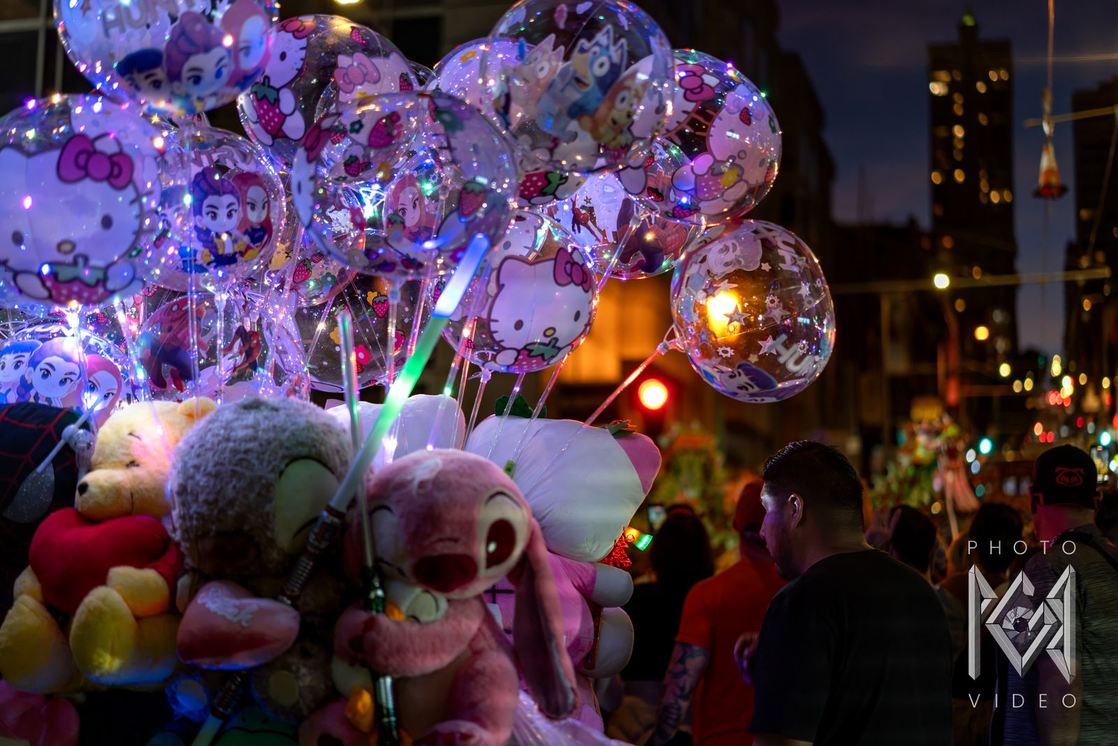 Light-up balloons and plush toys for sale above the parade crowd