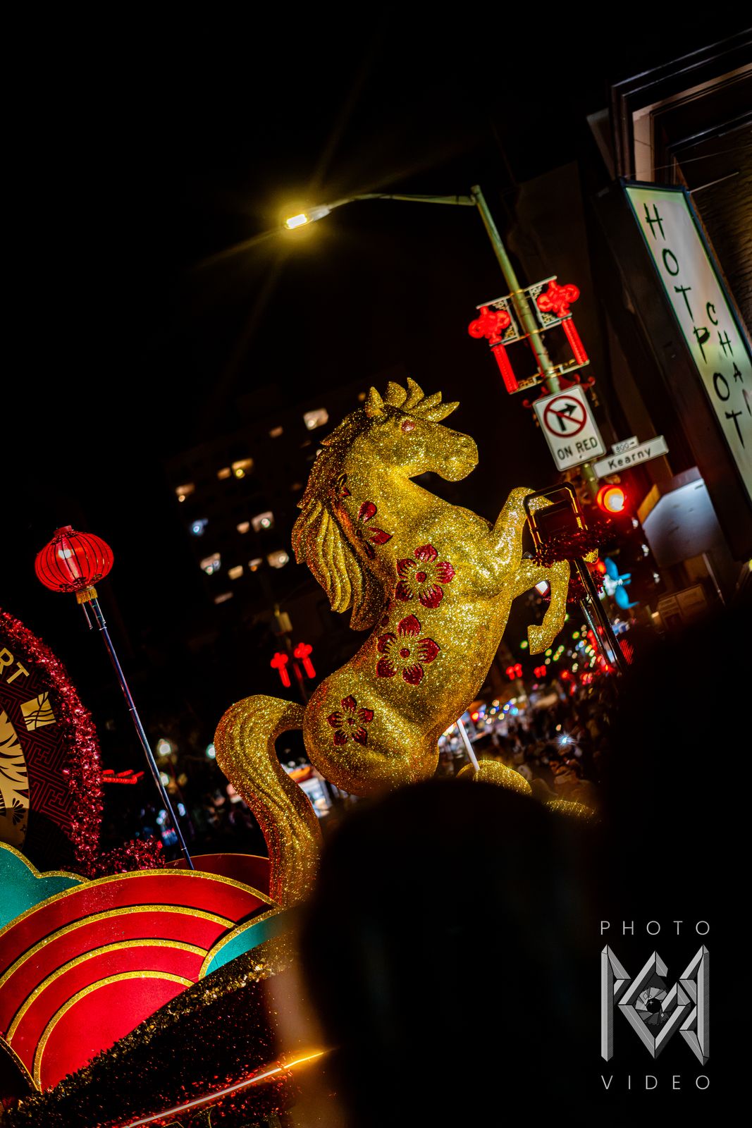 A golden horse float rearing up against the night sky beside a red lantern