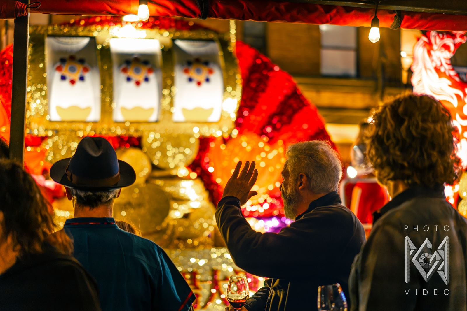 Spectators wave at a gold float decorated with a giant slot machine and a red fan