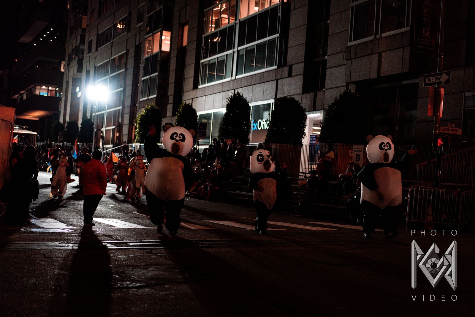Giant panda costumes walking down the dark street in the parade, casting long shadows