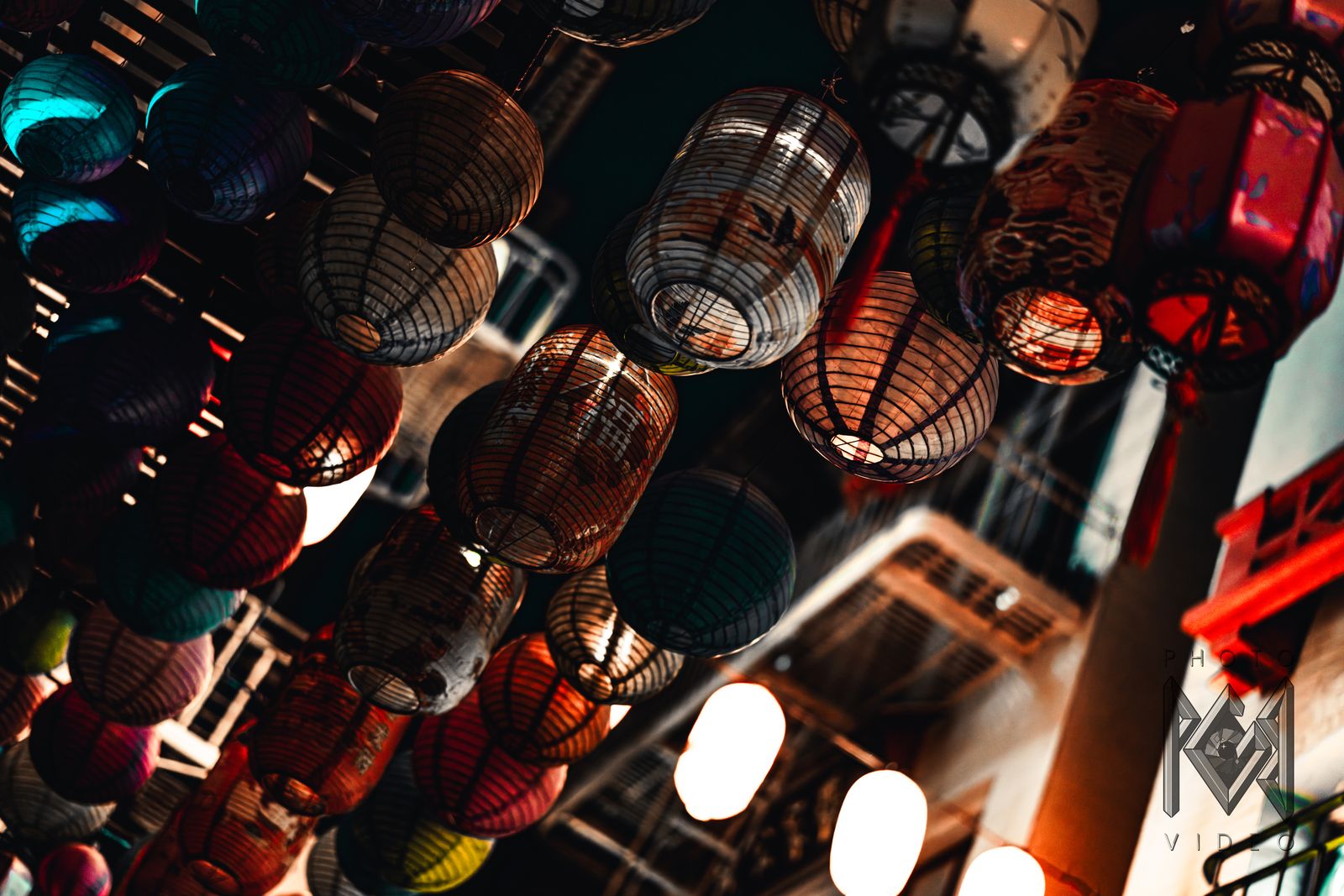 Rows of paper lanterns hanging over a Chinatown street, seen from below, in deeper colour