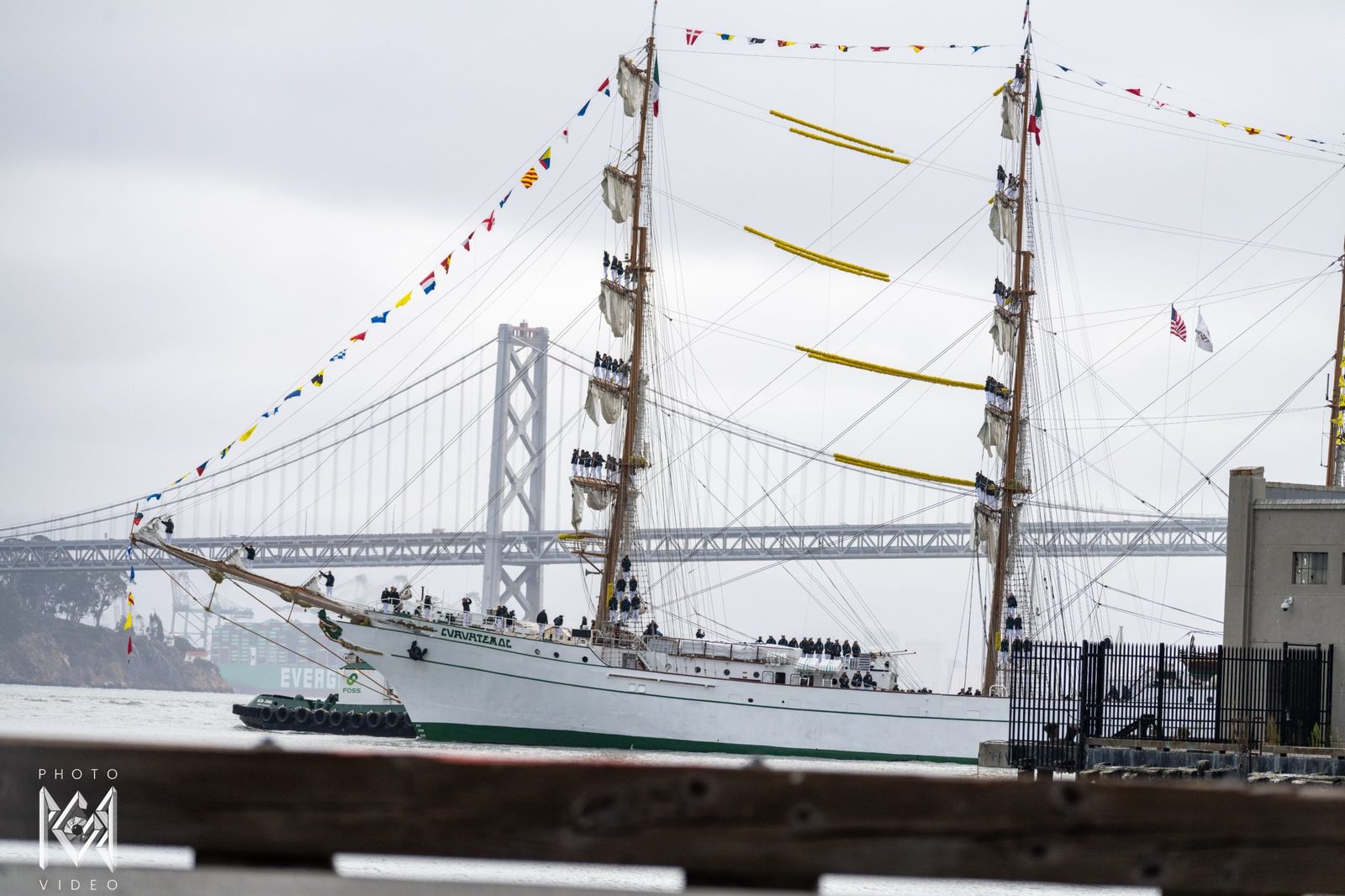 The ship passing in front of the bridge with crew standing on the yards