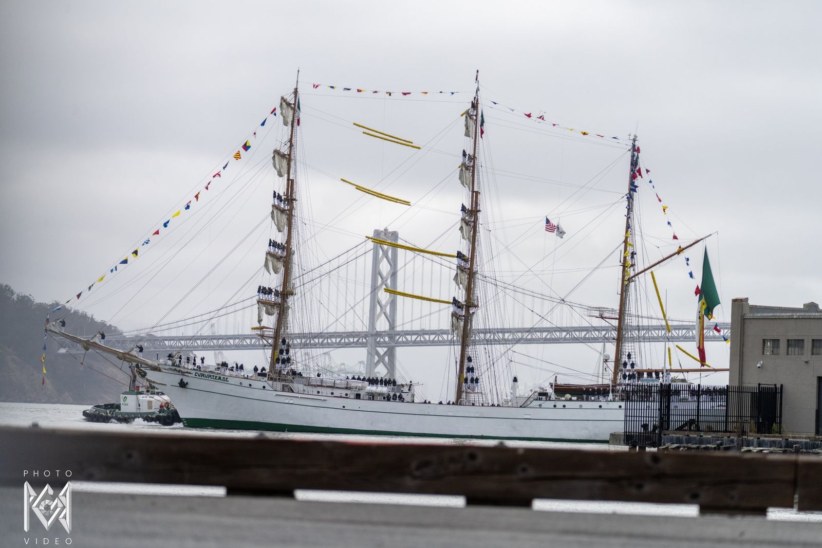 The ship arriving under the Bay Bridge, crew standing on the yards