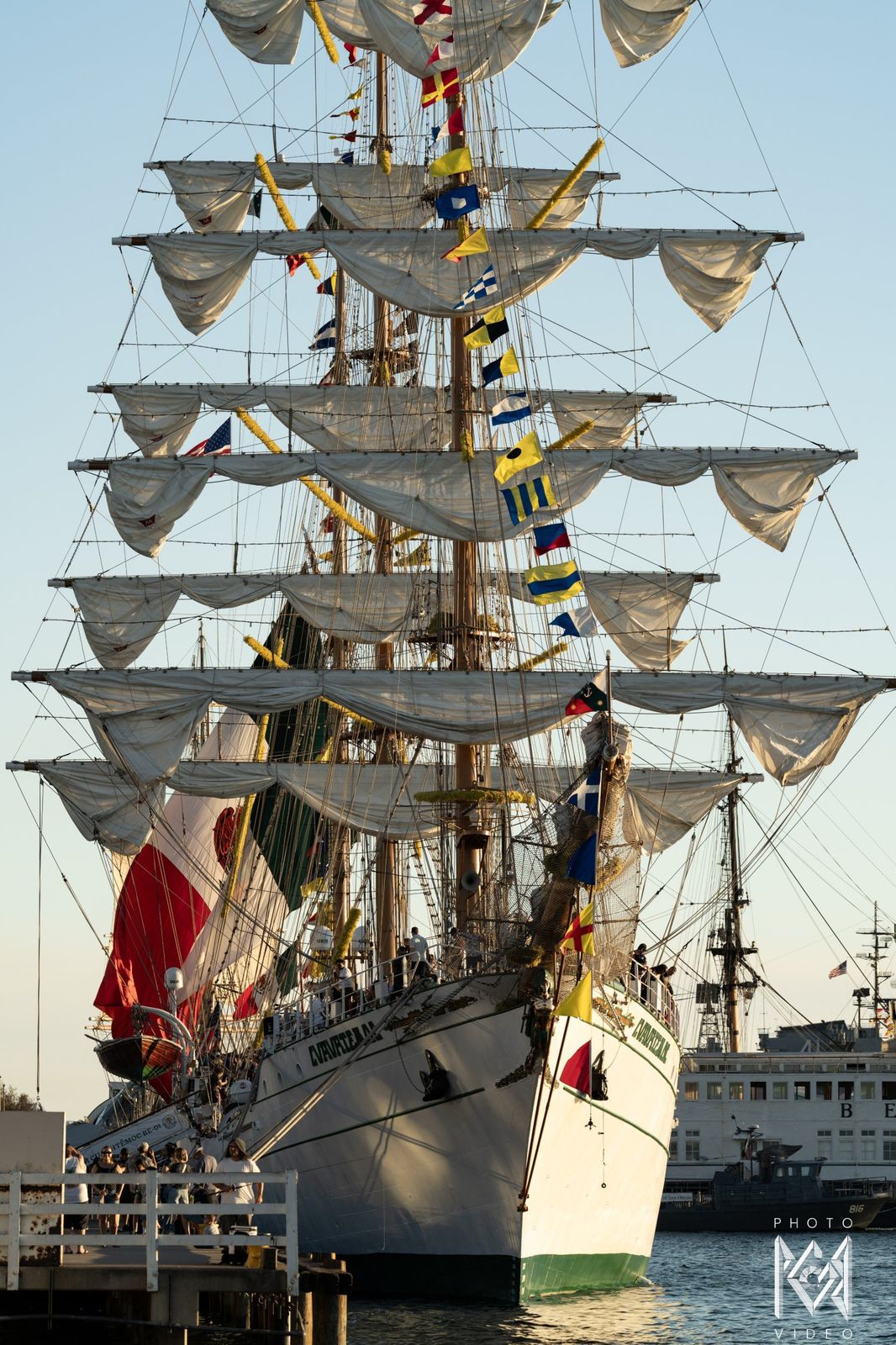 The ship's bow and rigging, signal flags and Mexican flags hanging from the yards
