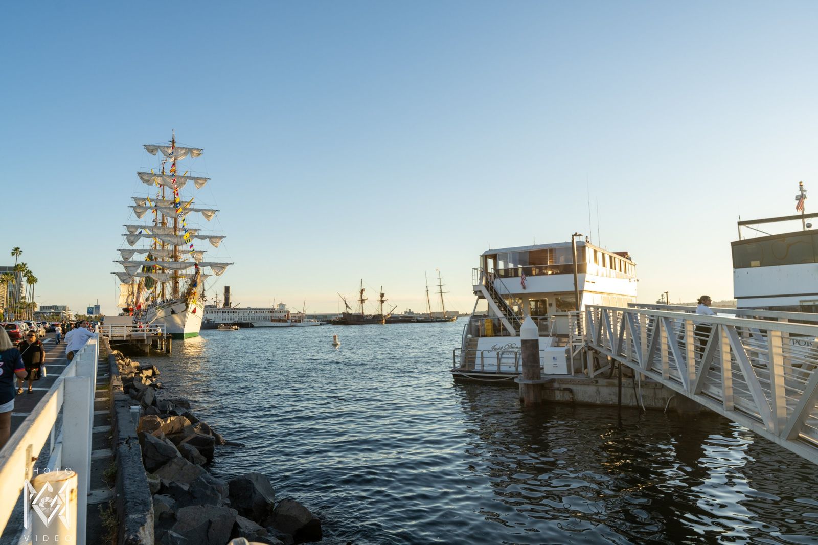 The ship moored at the end of a harbour walkway, a ferry at the dock beside it
