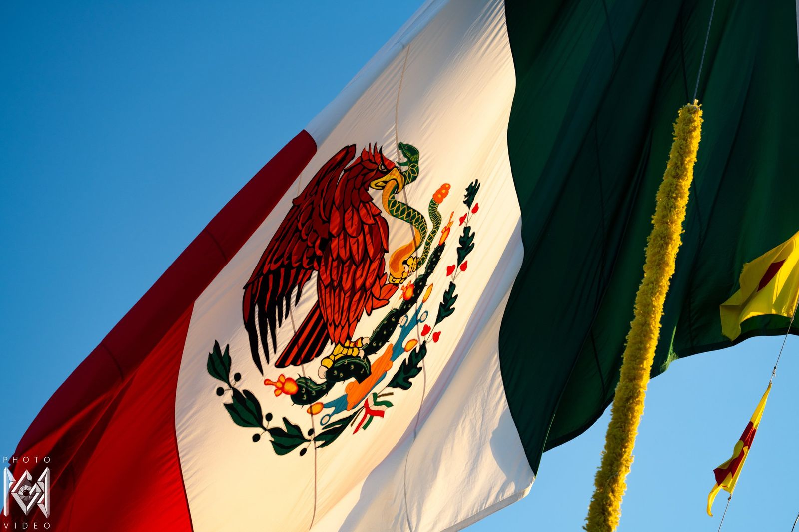 The Mexican flag, white, green and red, flying against a clear blue sky