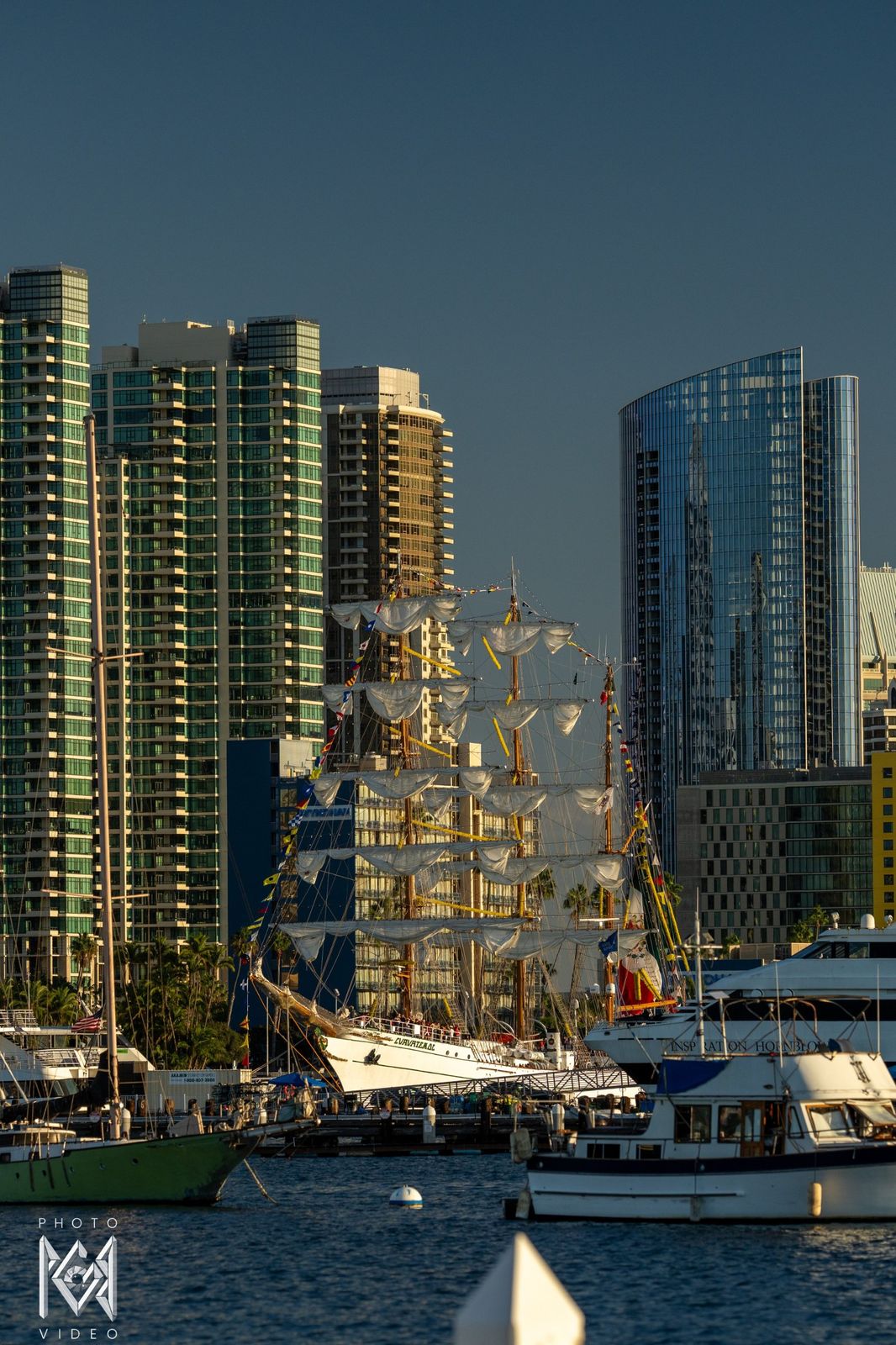 City towers across the water with the ship's masts rising between them