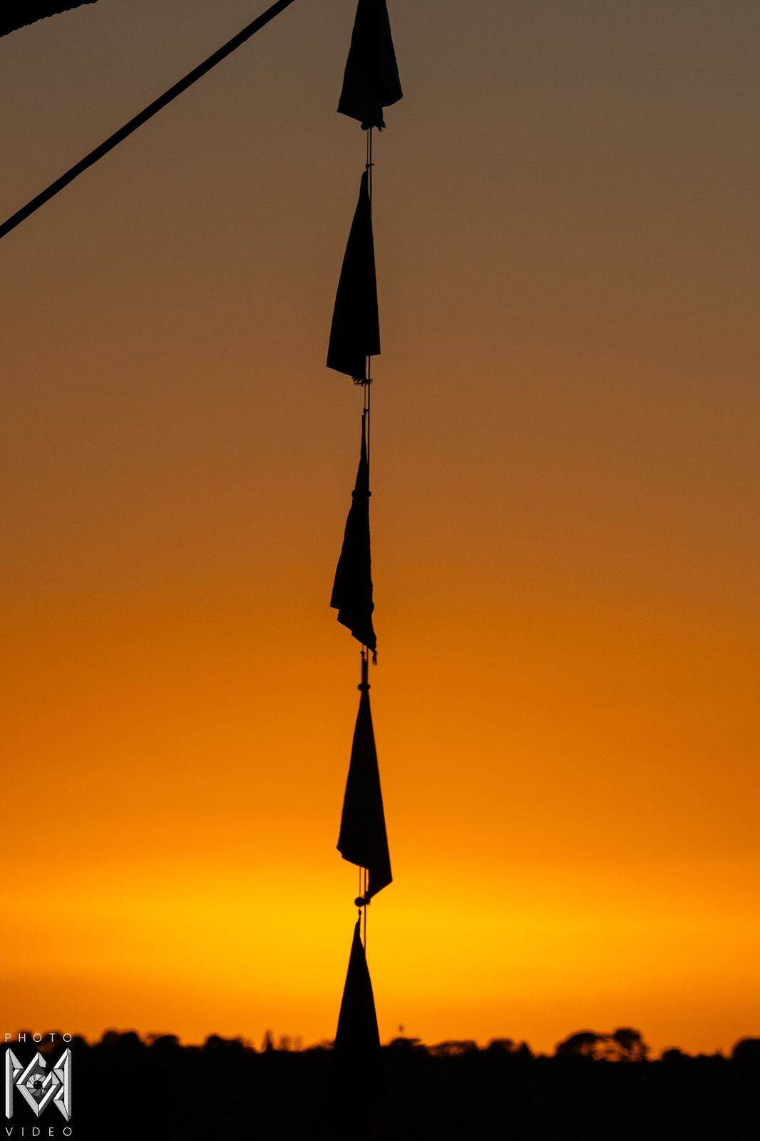 A string of signal flags hanging in silhouette against a glowing orange sky