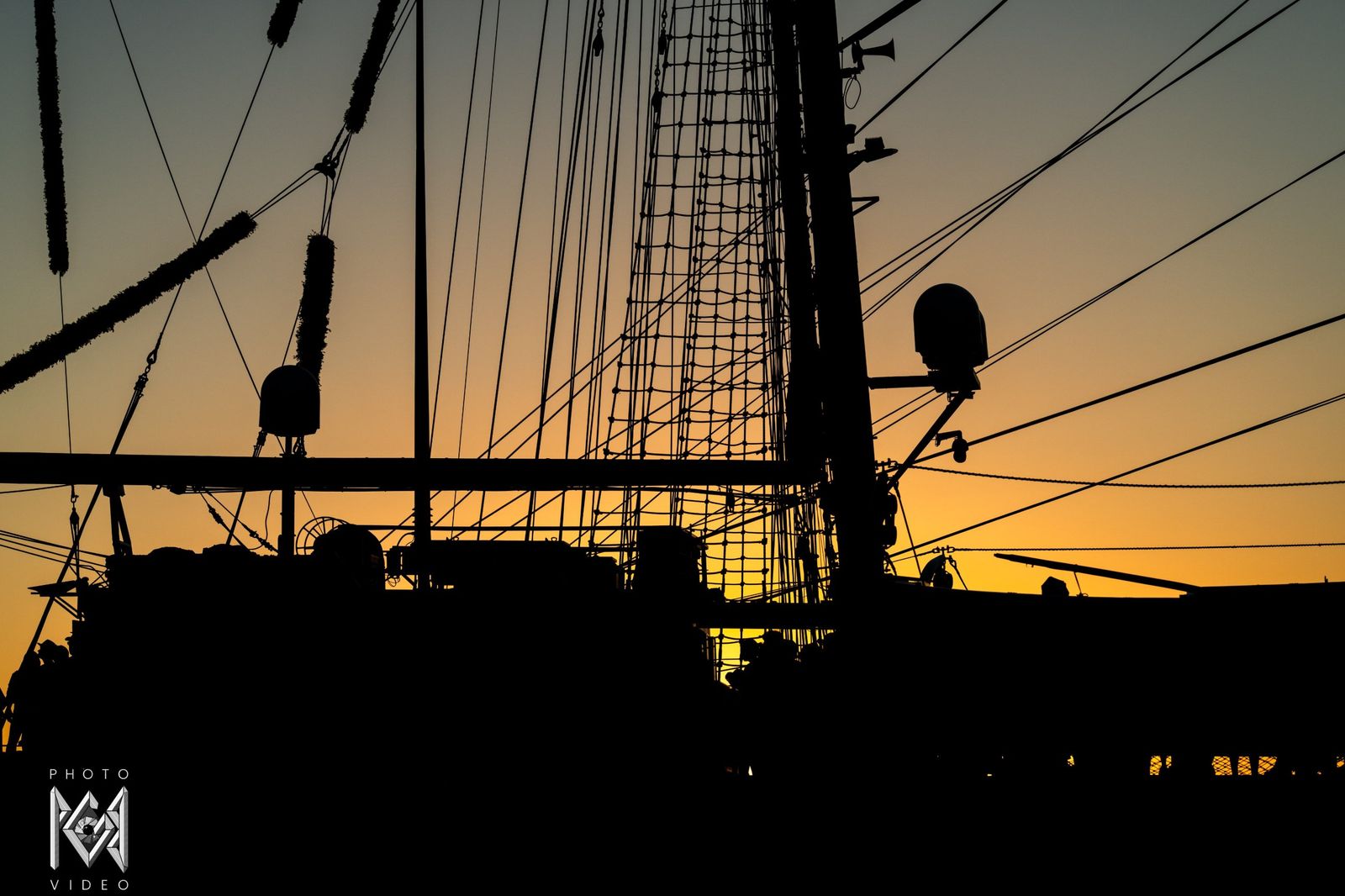 Rigging and masts in silhouette against the fading light