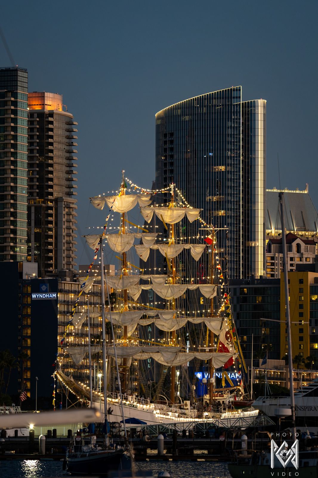 The ship lit among city towers at dusk
