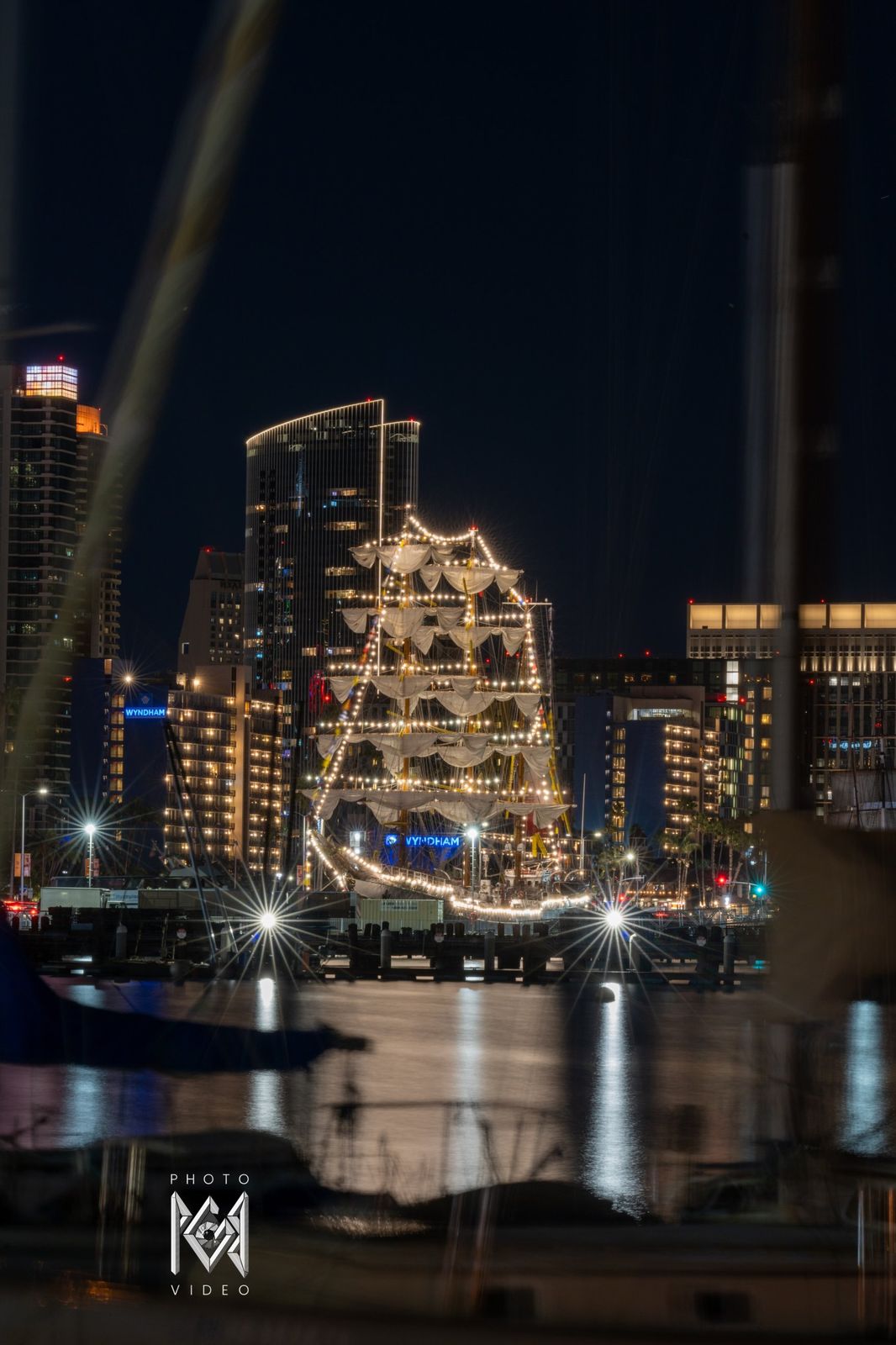 The ship outlined in strings of lights beside lit city towers at night