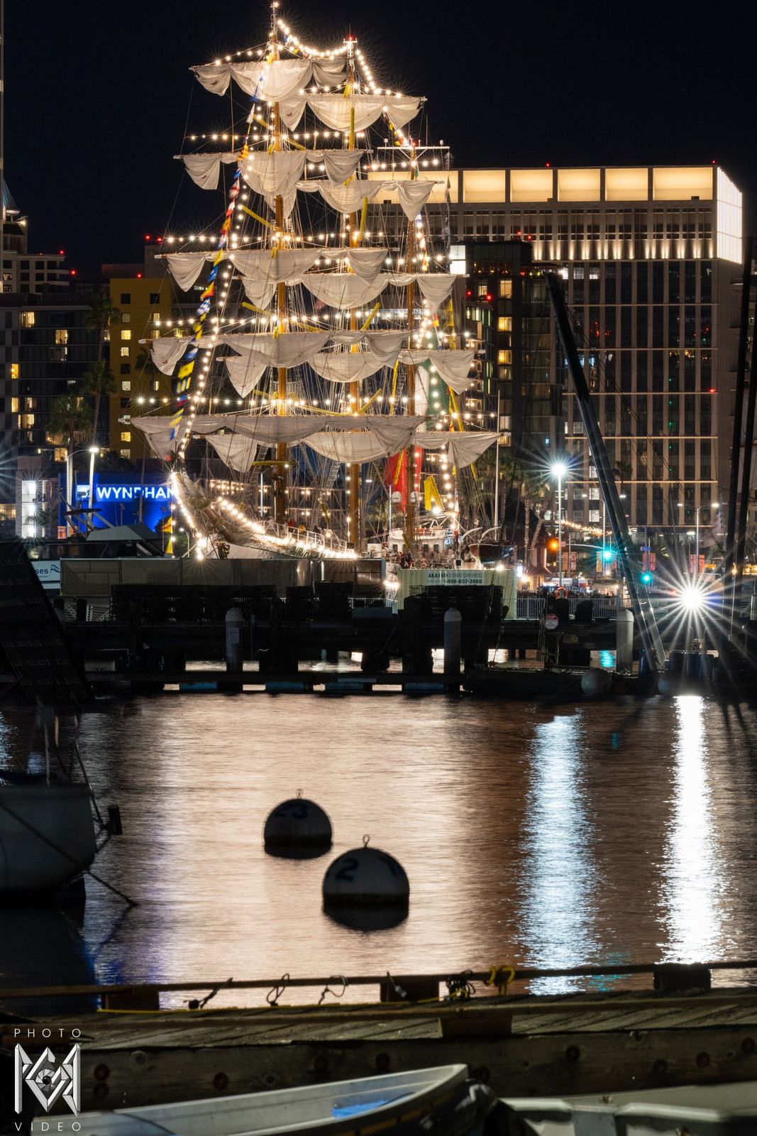 The illuminated ship above the dark harbour, her reflection and buoys in the water
