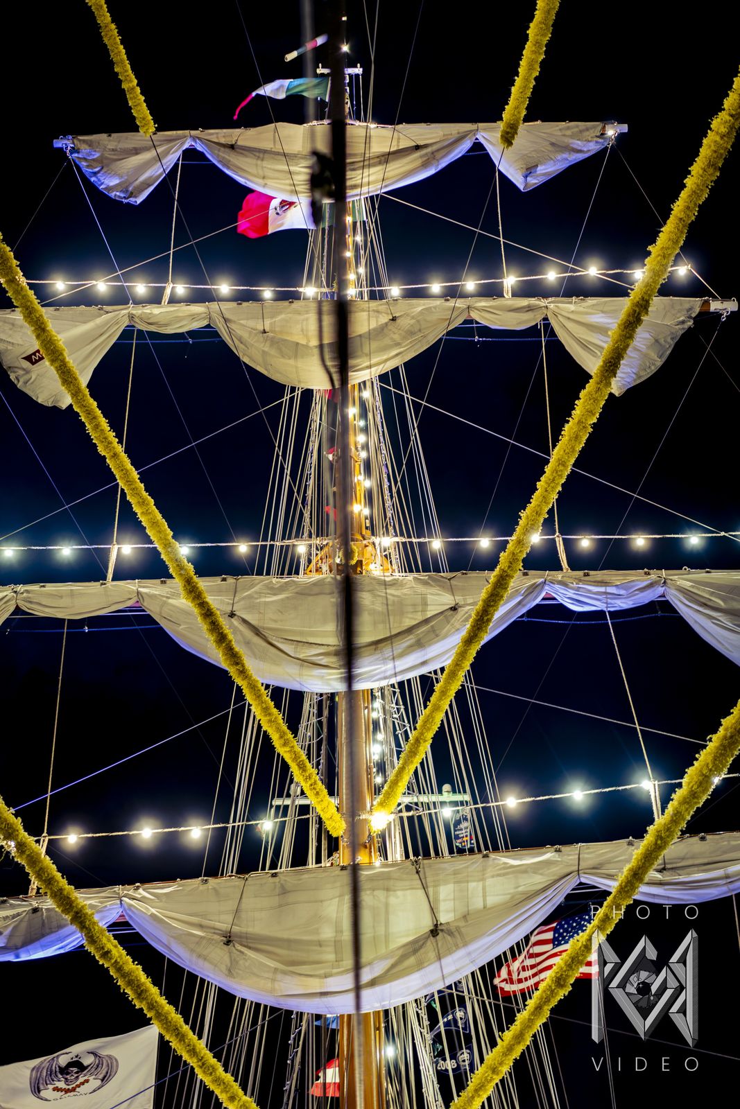 Yellow flower garlands crossing the ship's lit yards and string lights at night