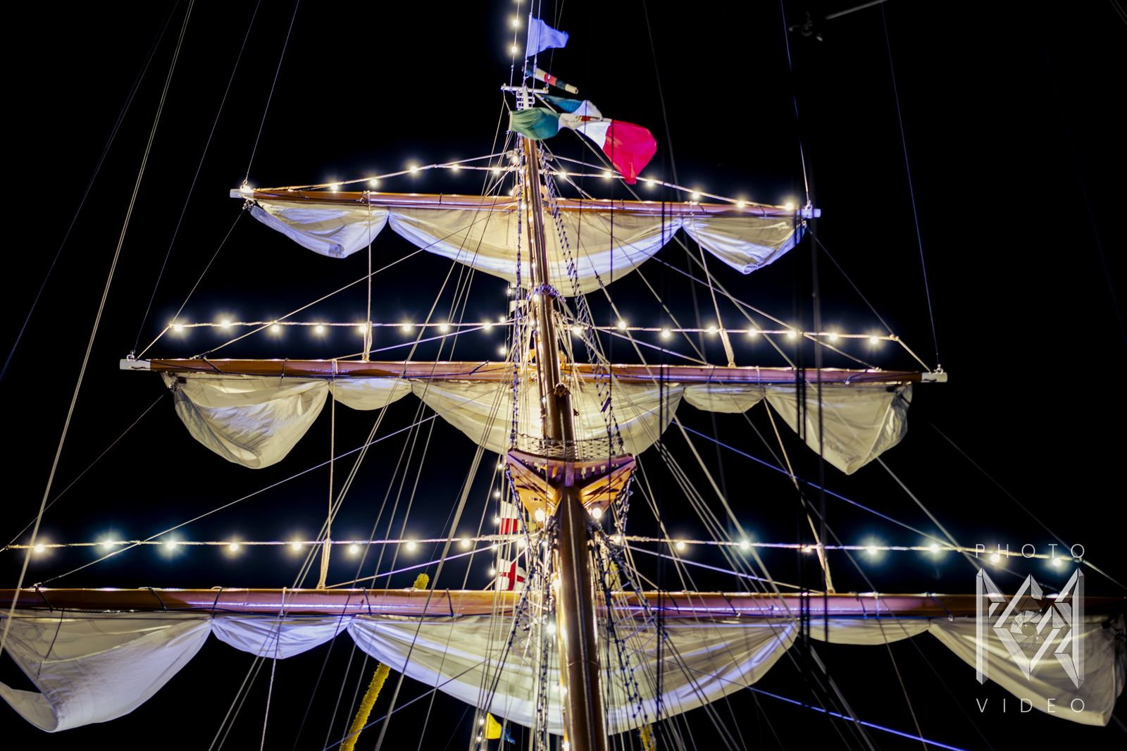 The lit yards and furled sails at the masthead, the Mexican flag above