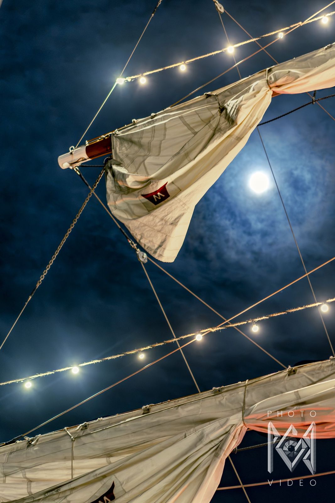The full moon among the furled sails and string lights