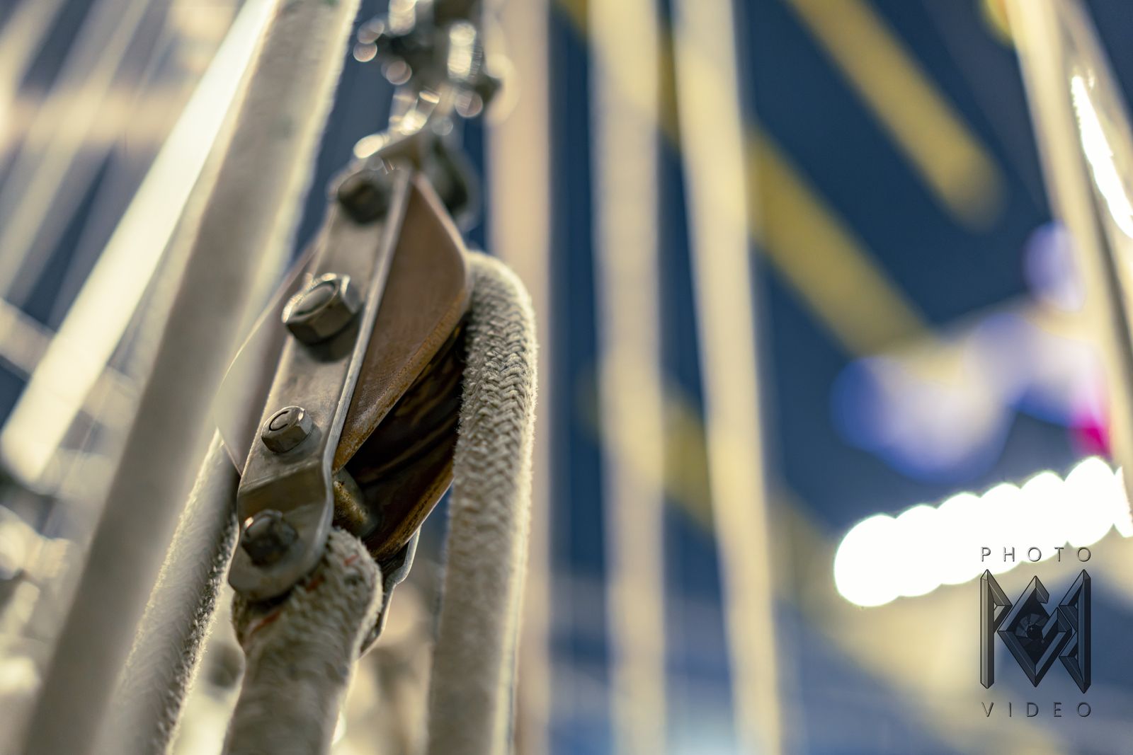 A wooden block and rope close up, the ship's lights blurred behind