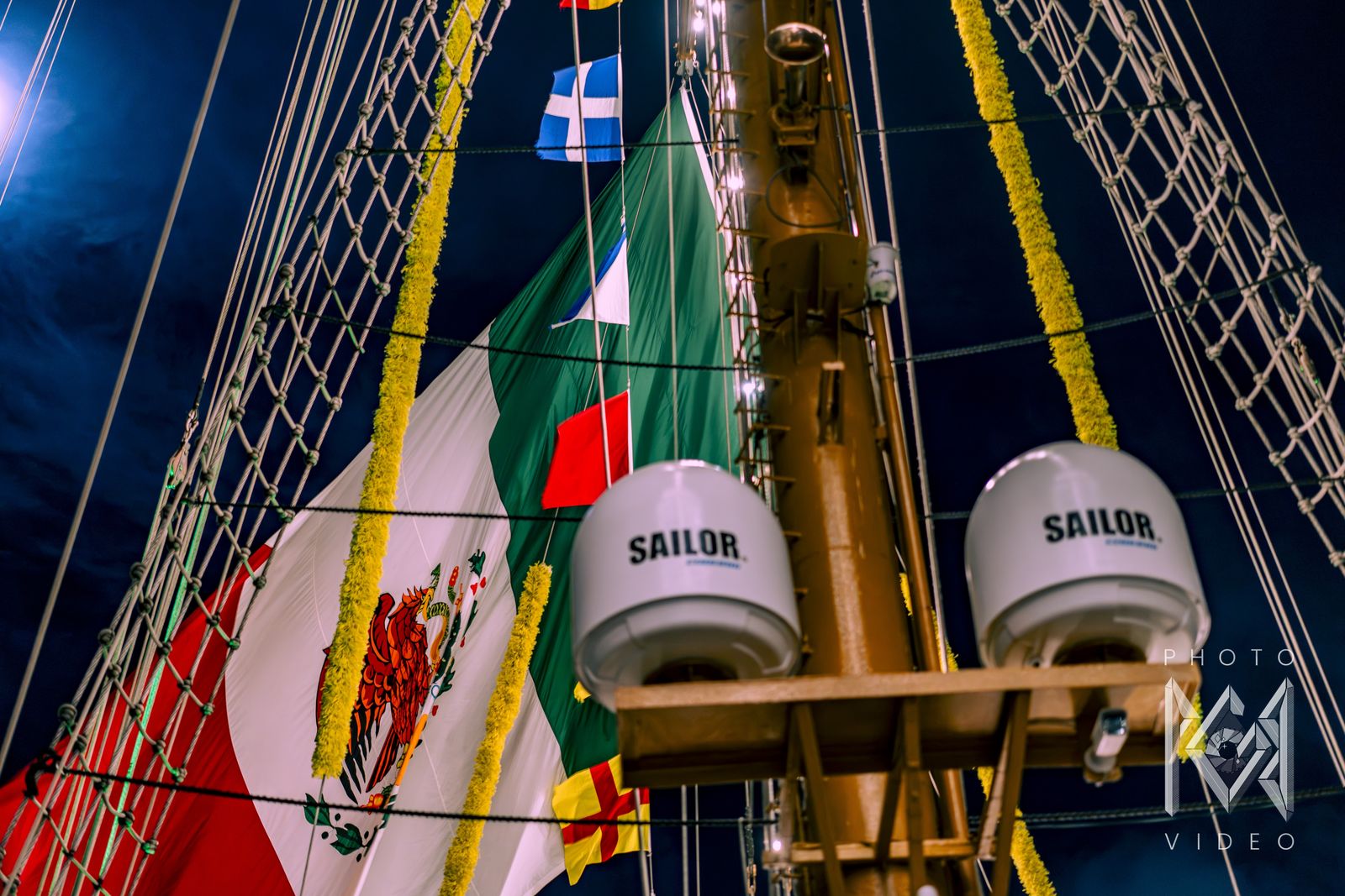 The Mexican flag and two satellite domes on the mast at night