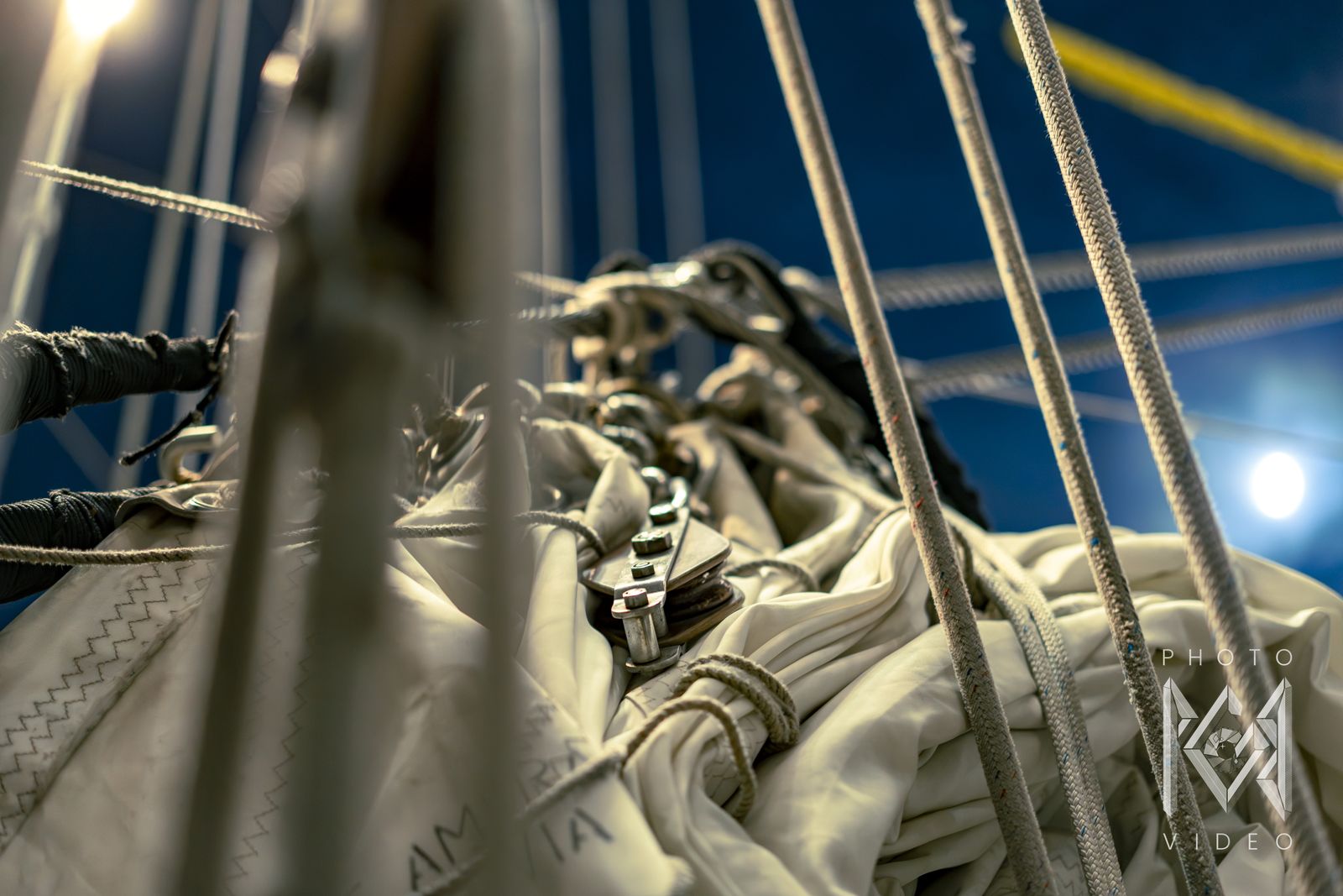 A pulley block among ropes and furled sail