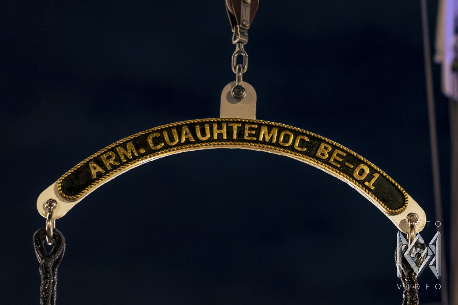 The ship's brass nameplate, ARM Cuauhtémoc BE-01, against the night sky