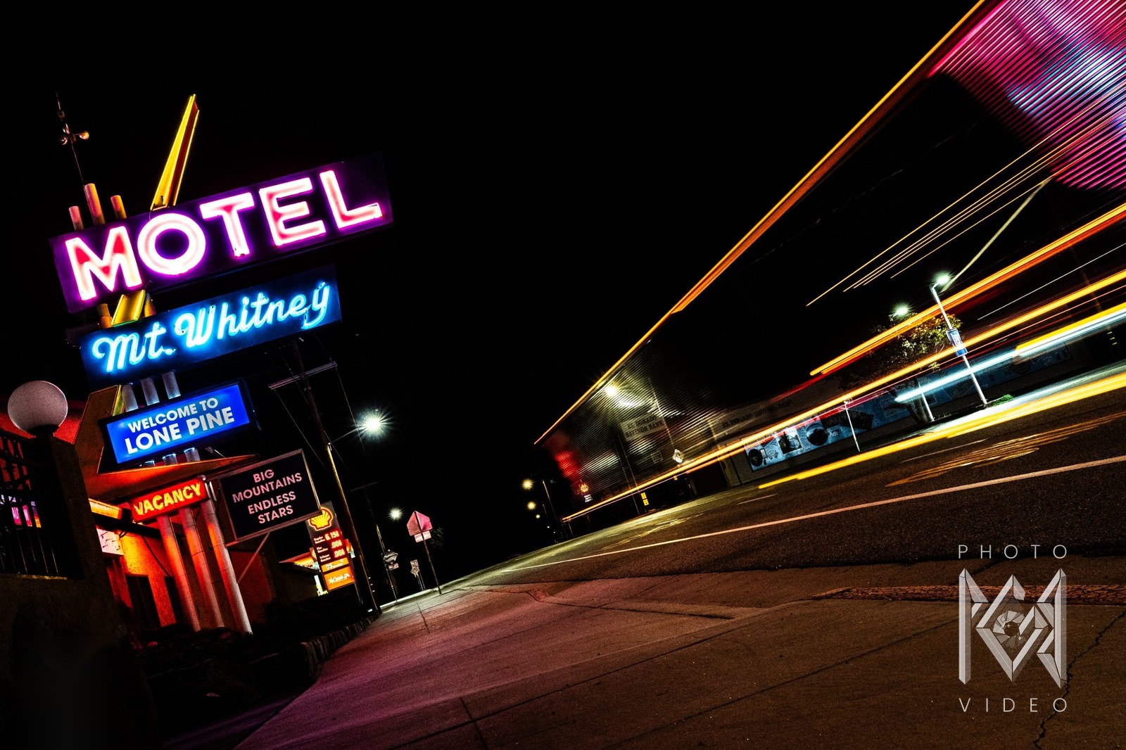 Lone Pine motel signs at night, MOTEL, Mt. Whitney and Welcome to Lone Pine, above a tilted street streaked with orange and yellow light trails