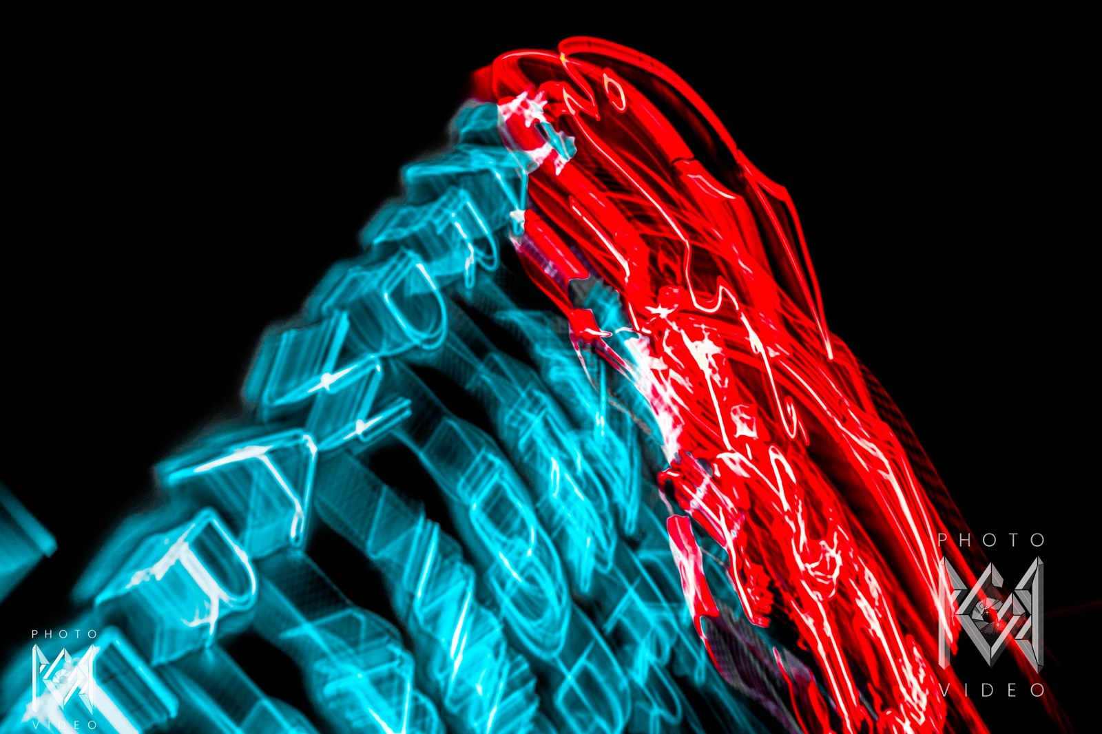 Neon motel lettering smeared into streaks of cyan and red light, an abstract blur of glowing tubes against black