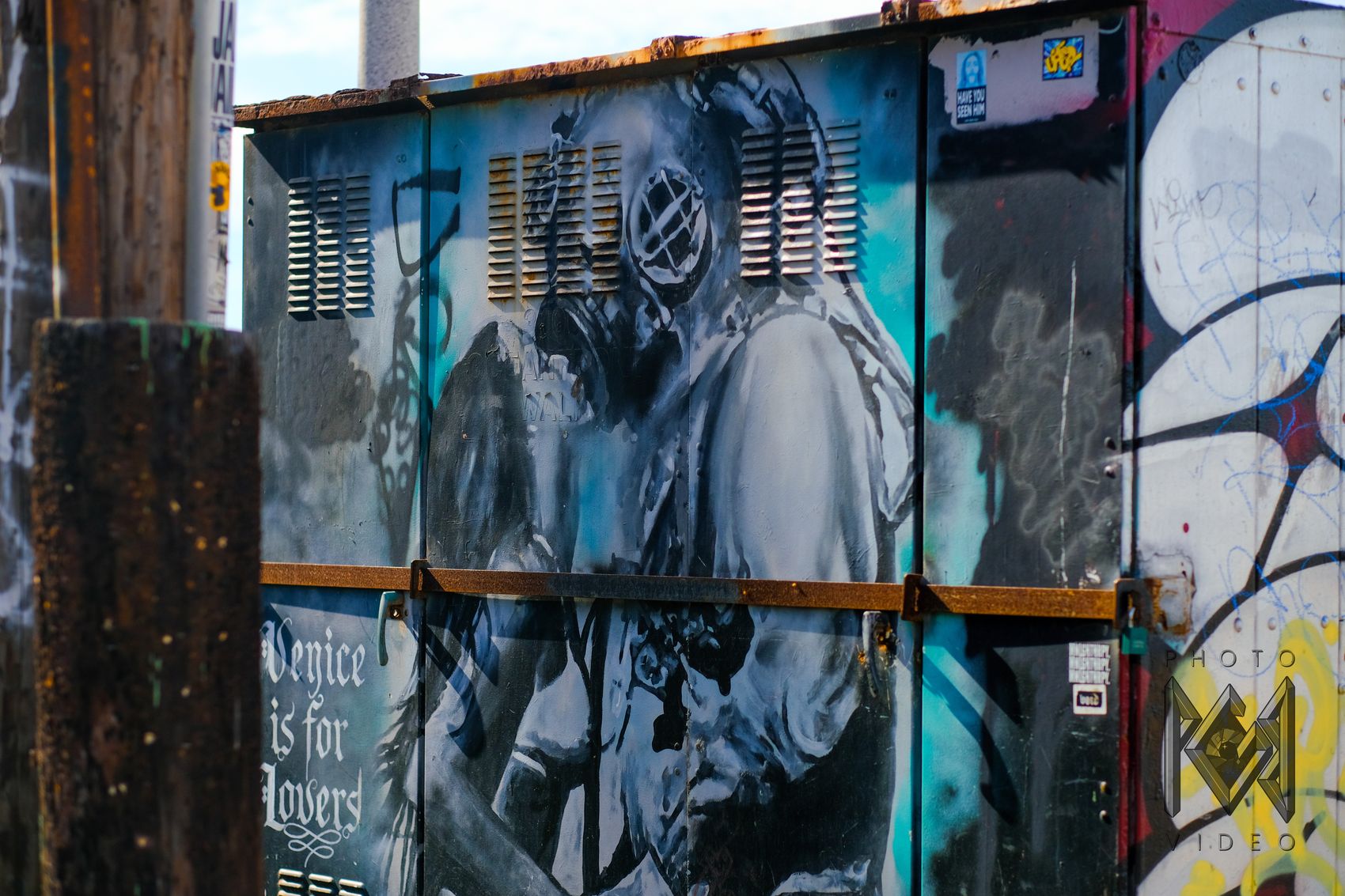 A painted utility box showing a diver in an old brass helmet embracing a woman, beside the words "Venice is for Lovers"
