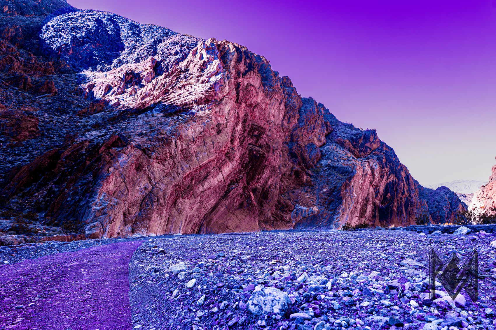 A great folded rock face in hot pink and rose above a stony wash of blue and violet pebbles, under a purple sky