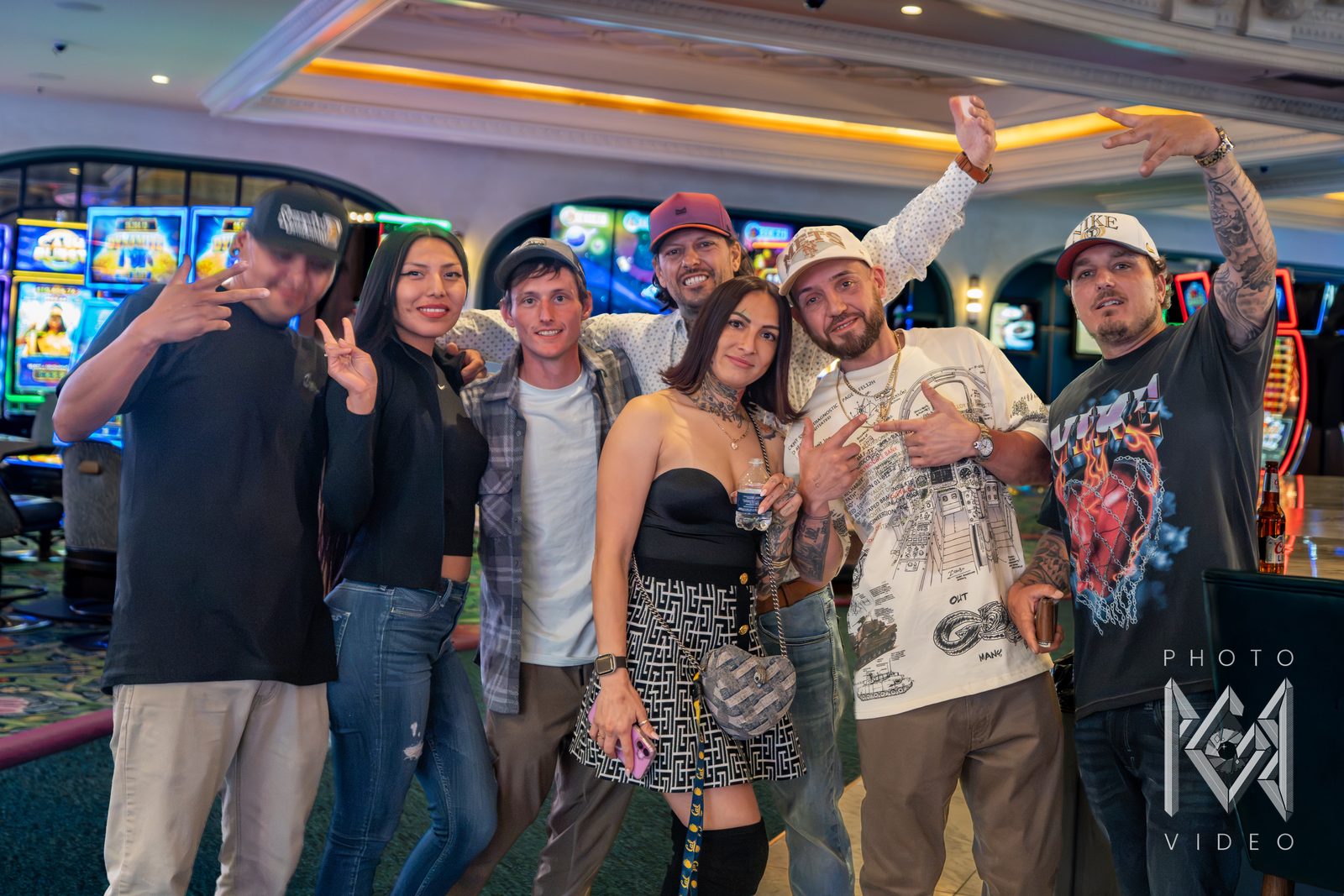 Patrick with a group of friends posing together on a brightly lit casino floor, smiling and throwing hand signs