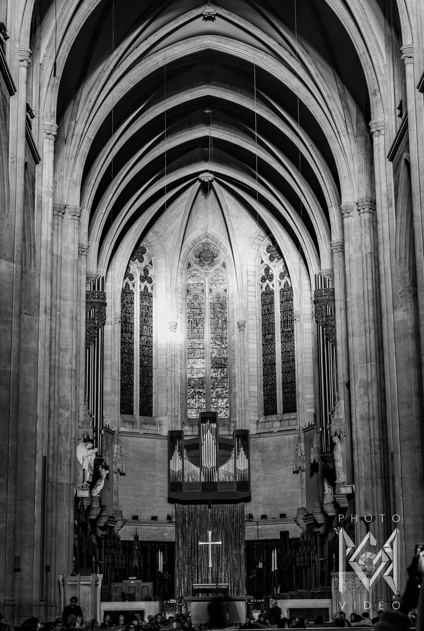 Black-and-white view down a Gothic cathedral nave toward its stained-glass windows