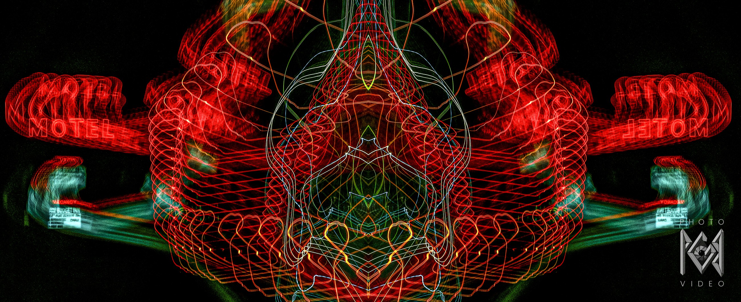 Red neon motel signs and looping trails of red, white, green and blue light, mirrored into a symmetrical figure