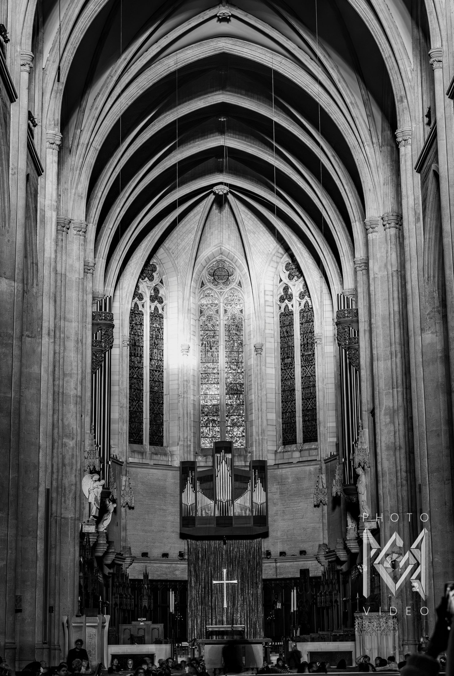 Black-and-white view down a Gothic cathedral nave toward its stained-glass windows